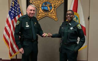 Sheriff Kitchings in uniform on left presenting Corporal stripes to Detention Deputy April Hernandez standing on the right in CCSO uniform